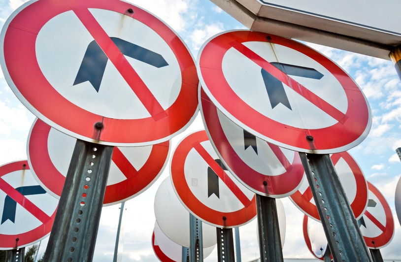 Understanding When It Is Actually Legal to Turn Left on Red in Texas Multiple no left turn traffic signs displayed together under a blue sky.