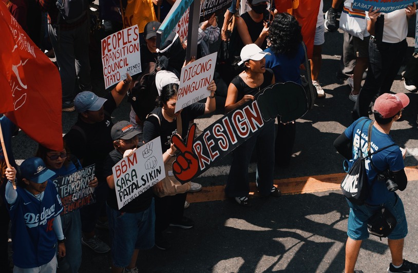 When Democracy Becomes a Zero-Sum Game: How Political Conflict Paralyzes Real Reform People rallying in urban protest with signs calling for political change.