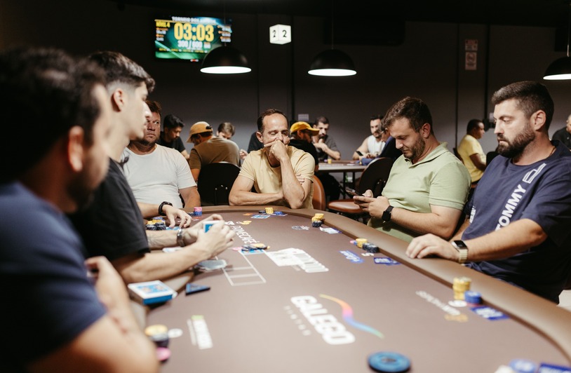 Group of men playing an intense poker game in a modern casino setting with focus on strategy.