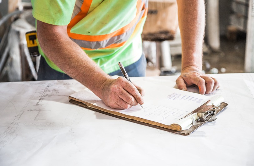 A construction worker in a hard hat reviewing documents at a job site