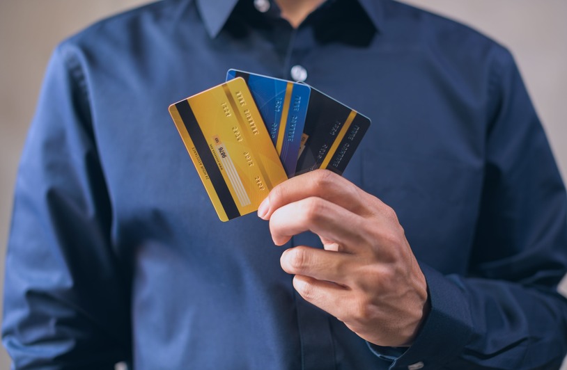 Person in a blue shirt holding three credit cards