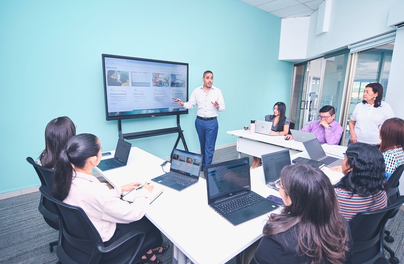 What to Know Before Choosing Among Free LMS Platforms for Teams Group of colleagues gathered around a laptop reviewing an online training course