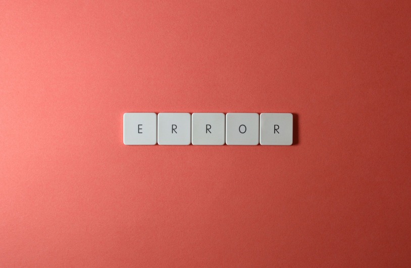 Five white square tiles spelling ERROR arranged in a row on a coral pink background