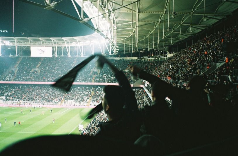 Wolves vs Port Vale: Match Analysis and What It Reveals About the Clubs Fans in silhouette waving scarves inside a large floodlit stadium with packed stands and players visible on the green pitch below