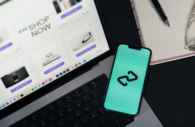 6 Best GEO Agencies for Marketplace Platforms A smartphone and laptop displaying online shopping platforms, suggesting digital retail.