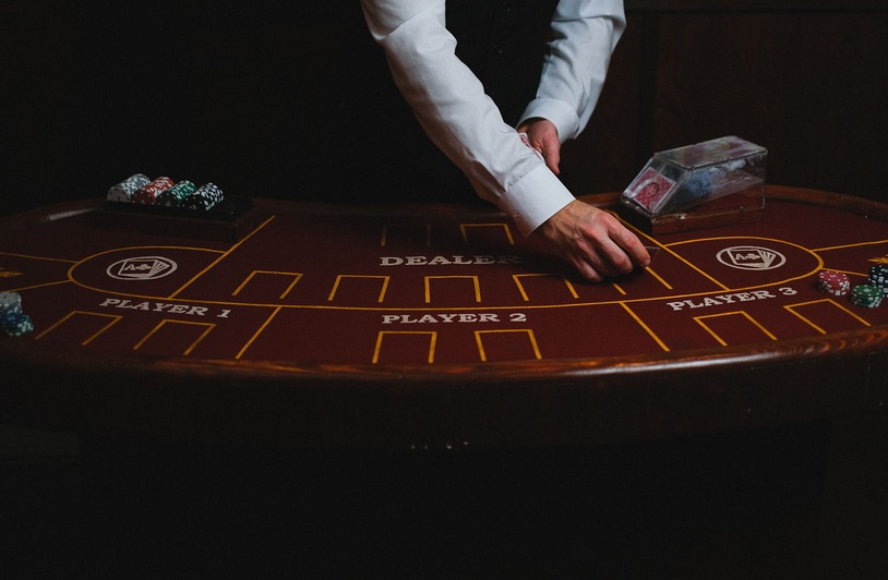 A croupier deals cards on a dimly lit casino table, showcasing gambling atmosphere.