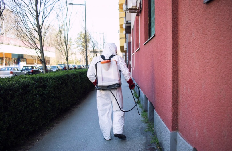 DCR-pest-control-simi-valley-Insert1 Worker in a protective suit spraying disinfectant outdoors